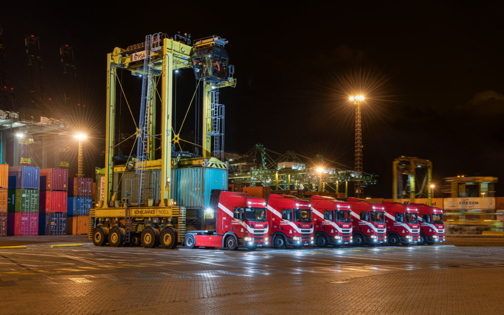 Sevral trucks from Transport Th. Wouters picking up containers at night at container terminal.